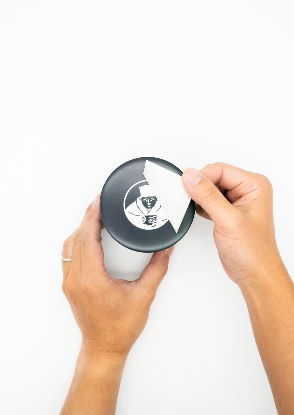 濃緑色の茶筒にイラストデザインのカッティングシートを貼っている